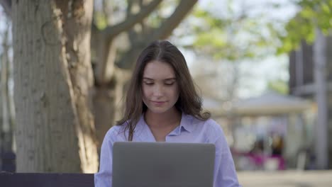 Medium-shot-of-pretty-Caucasian-woman-in-park-working-on-laptop